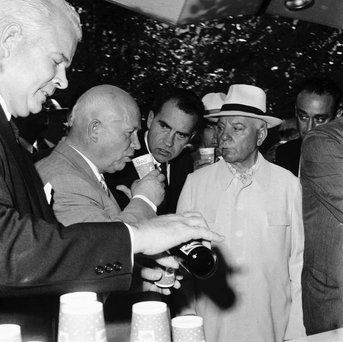 Микита Хрущов робить ковток Pepsi в 1959 році на Національній виставці США в Москві, в той час як Річард Ніксон спостерігає, а Дональд Кендалл наливає ще одне паперове горня